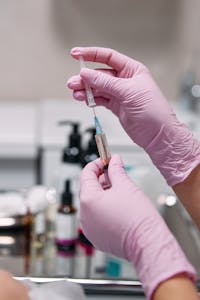 Person Wearing Latex Gloves Holding Syringe